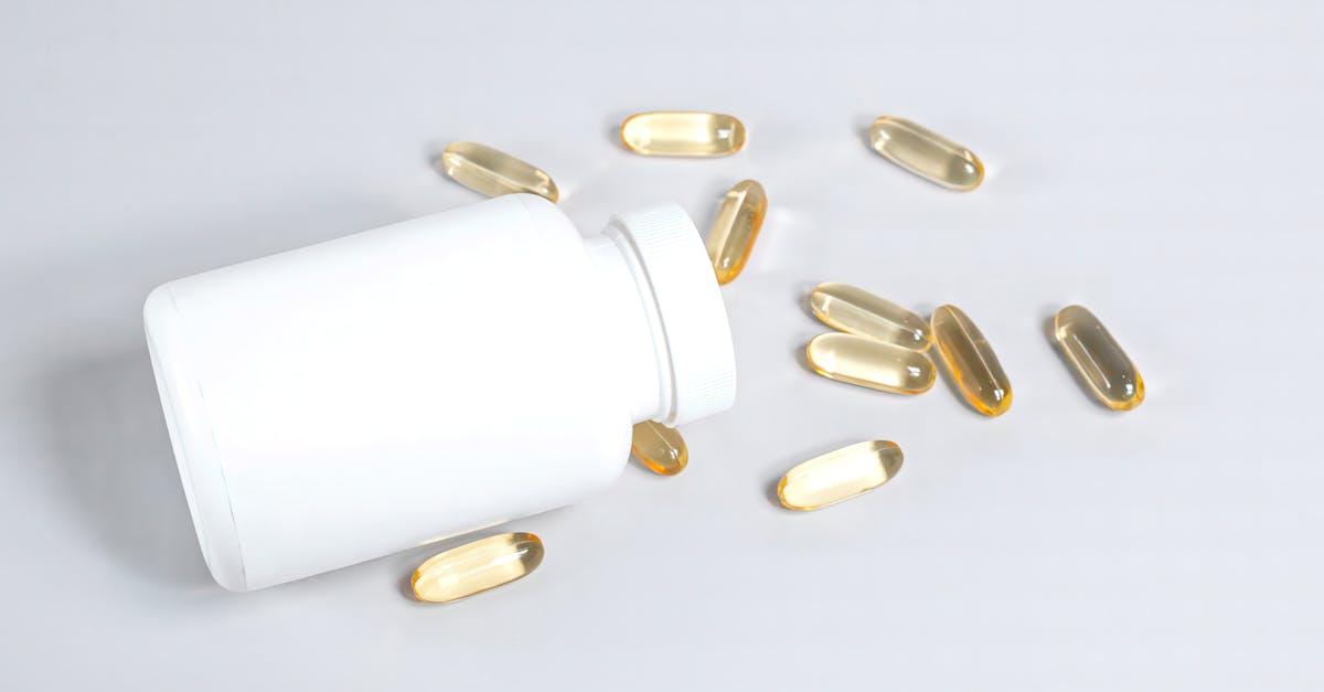Healthy fish oil capsules spilled from a white bottle on a smooth white surface.