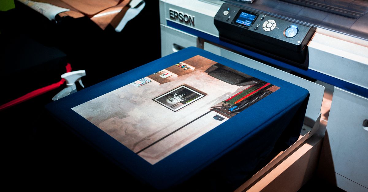 Close-up of a professional printer printing a custom artwork design on fabric in a studio setting.