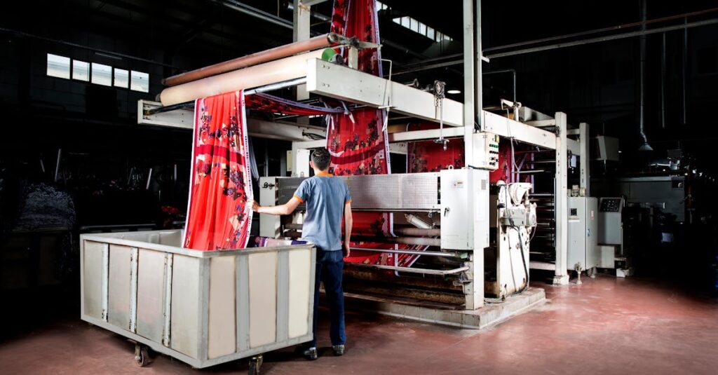 Worker operates machinery in a textile factory, overseeing fabric production.