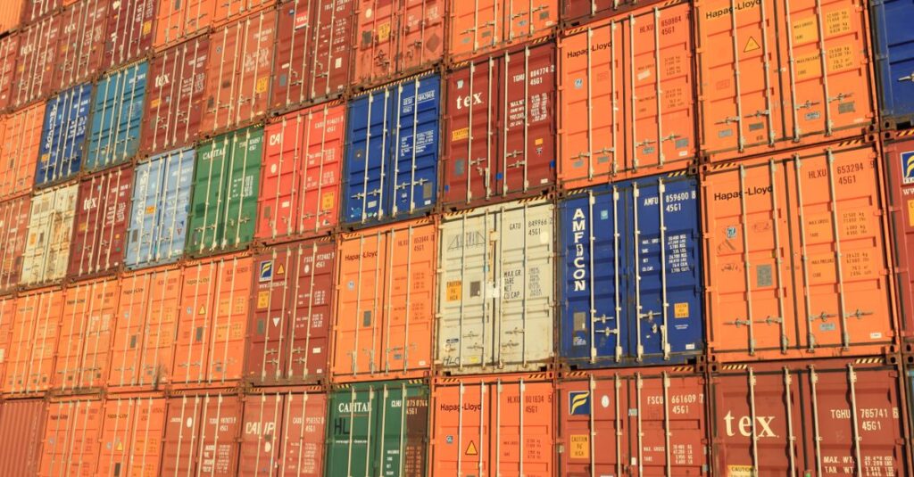 Colorful shipping containers stacked in a harbor, symbolizing global trade.