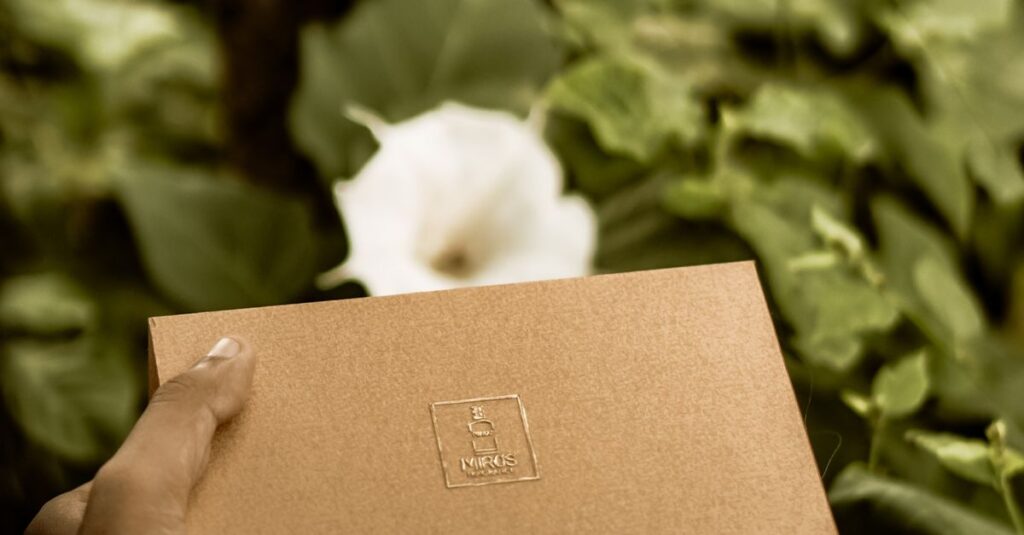 Brown craft box held by hand amidst lush green foliage in a serene garden setting.