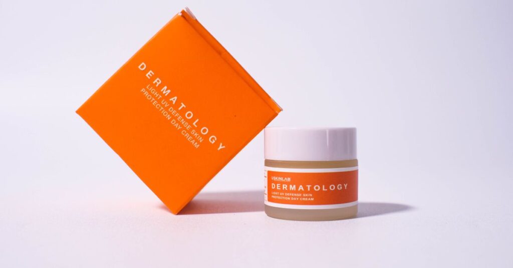 Bright orange dermatology cream packaging on white background for skincare advertisement.