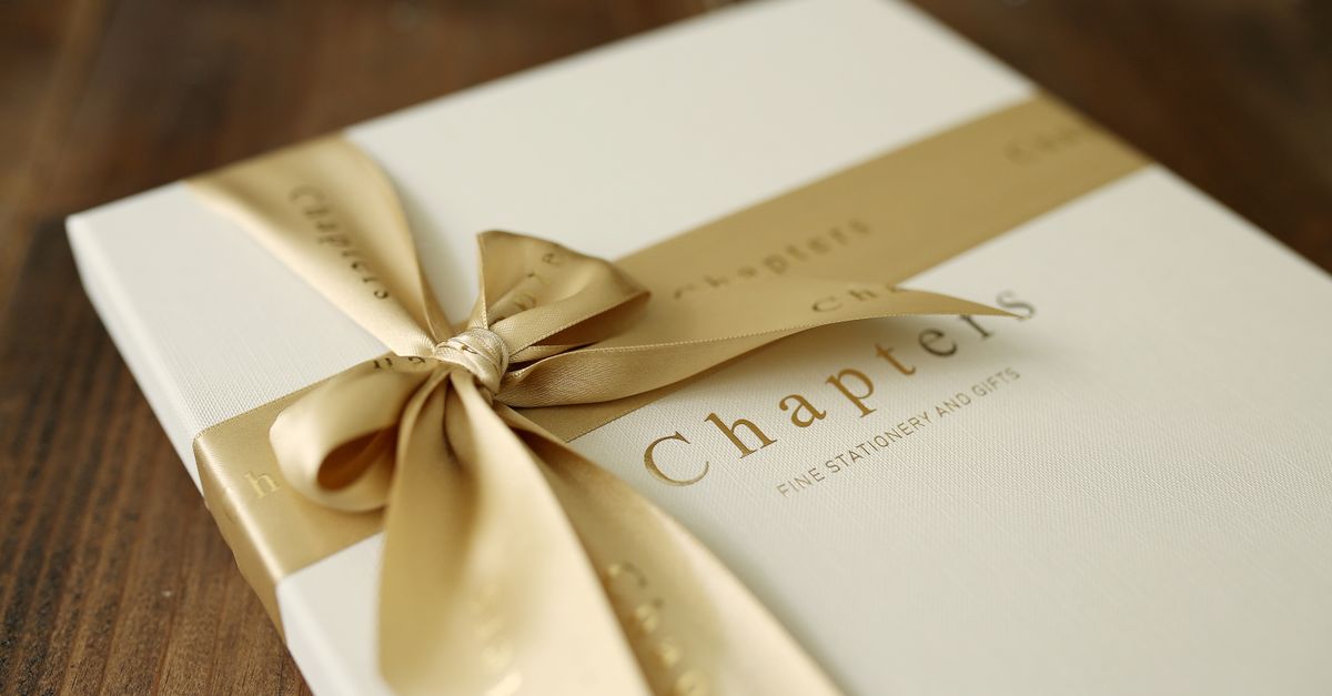 A close-up of an elegant gift box wrapped in a golden ribbon, placed on a wooden surface.