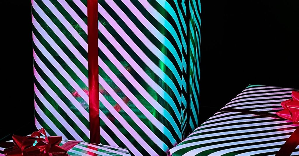 Vibrant gift boxes wrapped in striped paper with red bows on a black background. Ideal for holiday themes.
