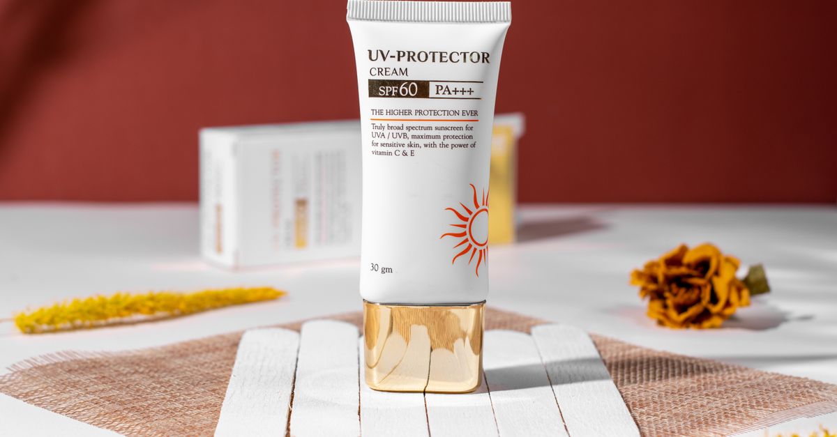 Close-up of SPF 60 UV protection cream for skincare, featuring floral accents and a natural setting.