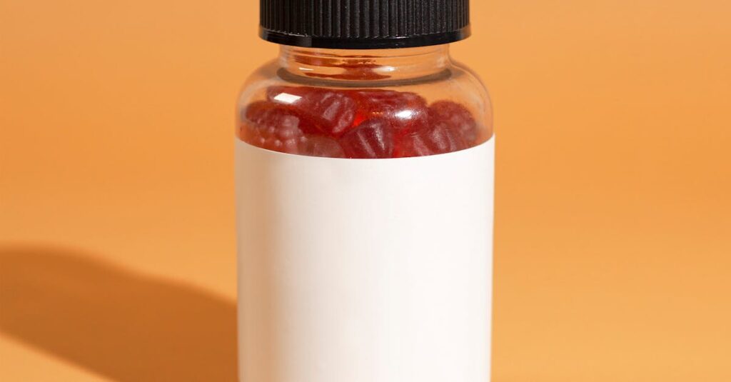 Clear bottle filled with red gummies on an orange background, perfect for supplement mockups.