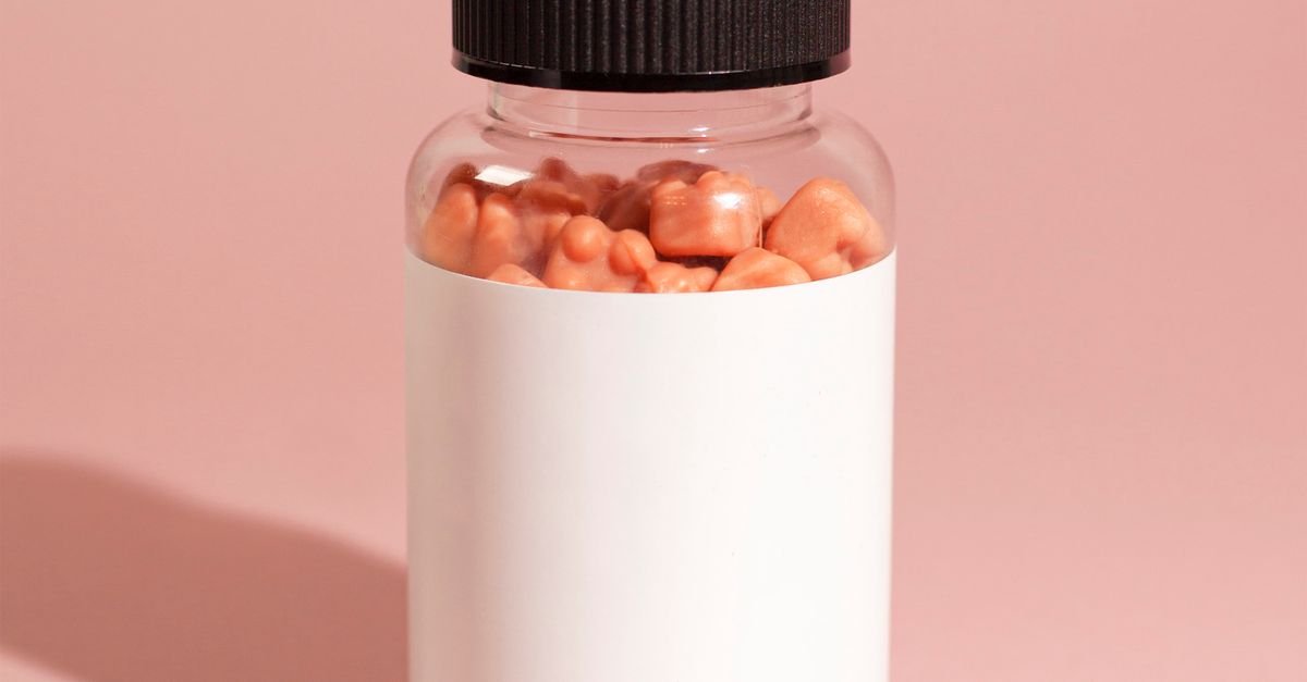 Close-up of vitamin gummies in a labeled bottle on a pink background, ideal for health-related products.