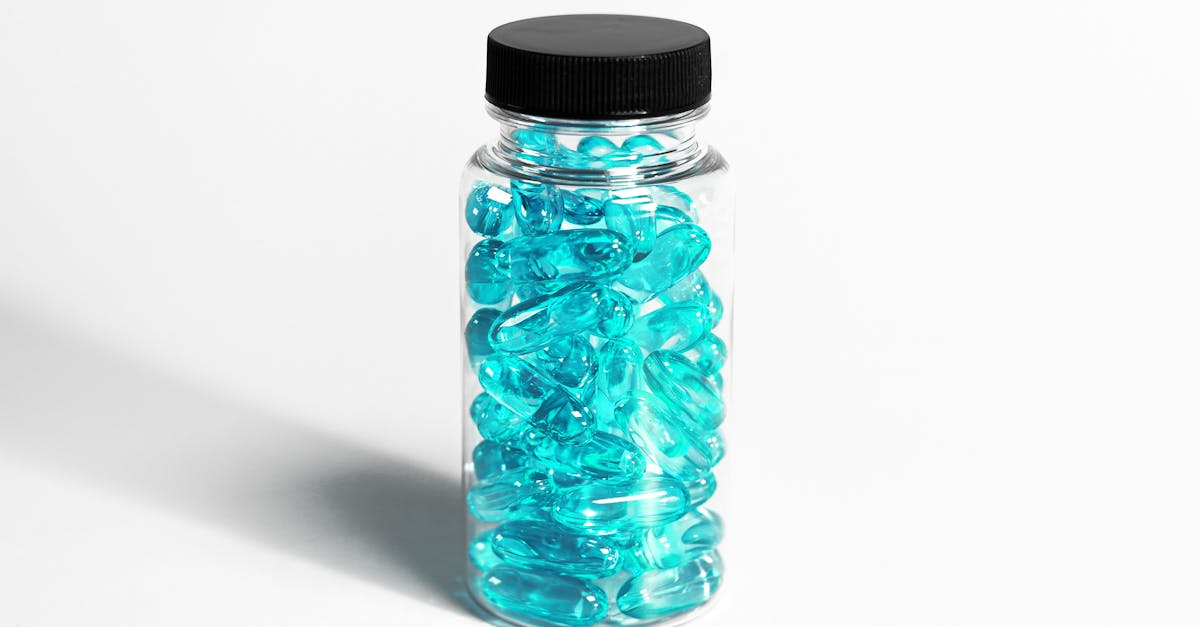 A clear bottle filled with turquoise capsules, showcasing healthcare and nutrition themes.
