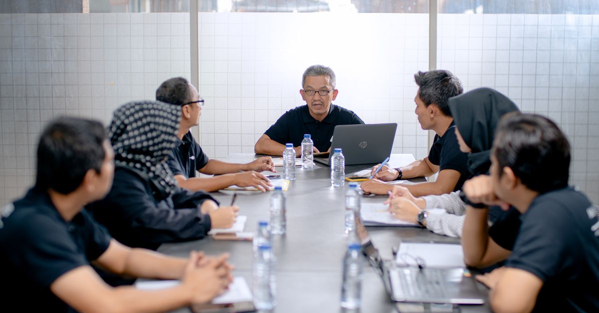 Professional team meeting around a conference table in an office setting.
