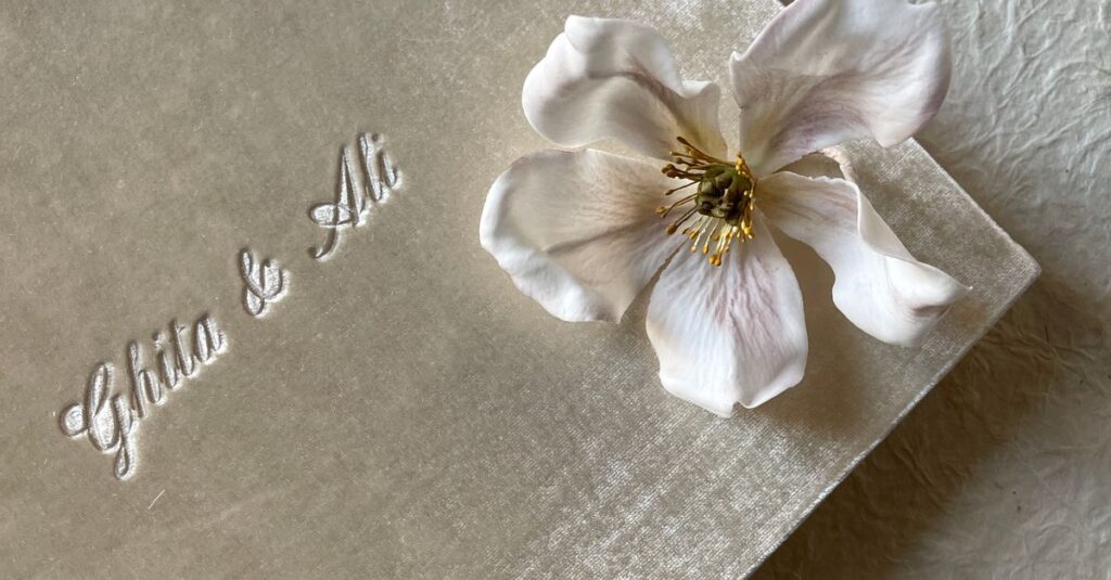 Elegant gift box with a white flower and embossed text on a textured surface.