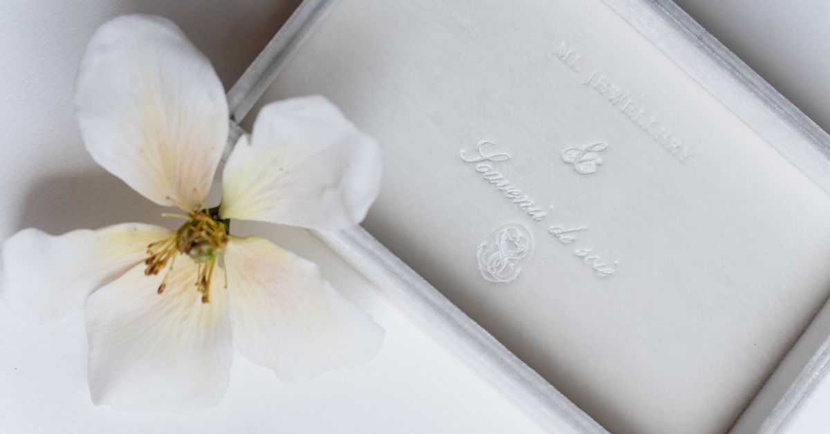 An elegant jewelry box paired with a delicate white flower on a soft background.