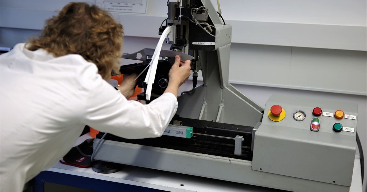 Scientist operates a precision testing machine in a modern laboratory setting.