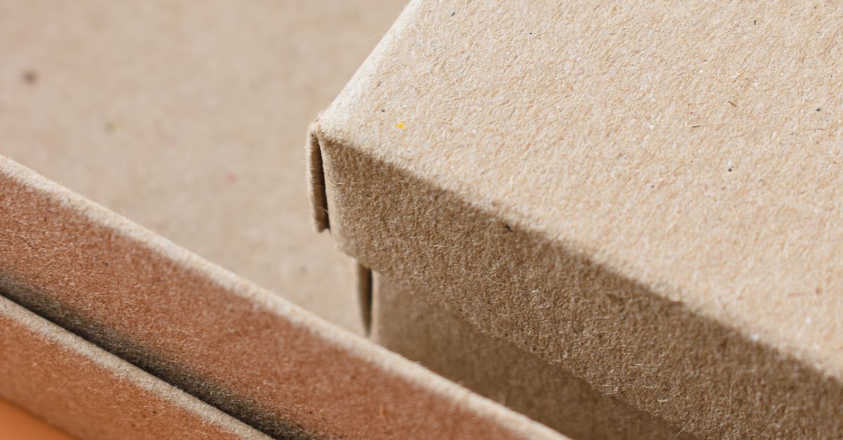 Minimalist close-up of eco-friendly cardboard packaging boxes on an orange background.