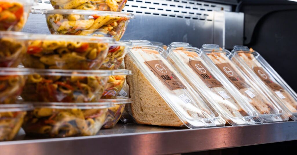 Delicious ready-to-eat pasta salads and sandwiches displayed in a store fridge.
