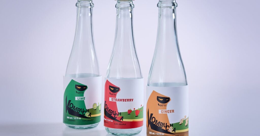 Three labeled kombucha bottles featuring lime, strawberry, and ginger flavors on a white surface.