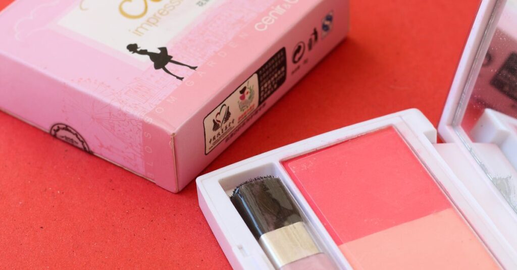 Colorful makeup palette with brush on a red background, perfect for beauty and cosmetic themes.