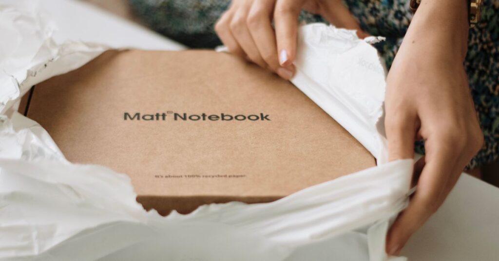 Close-up of hands unboxing a Matt notebook made from recycled paper, emphasizing sustainability.