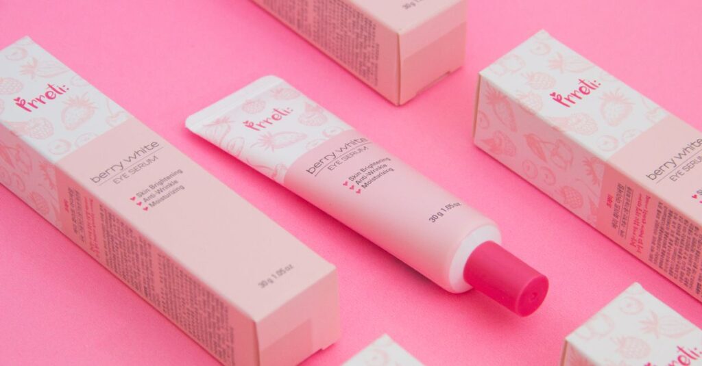 Pink-themed flat lay of berry-white eye serum with packaging.