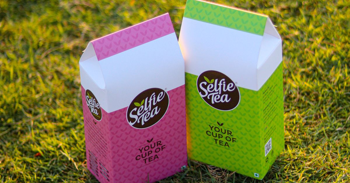 Colorful tea packaging boxes outdoors on grass, ideal for product photography.