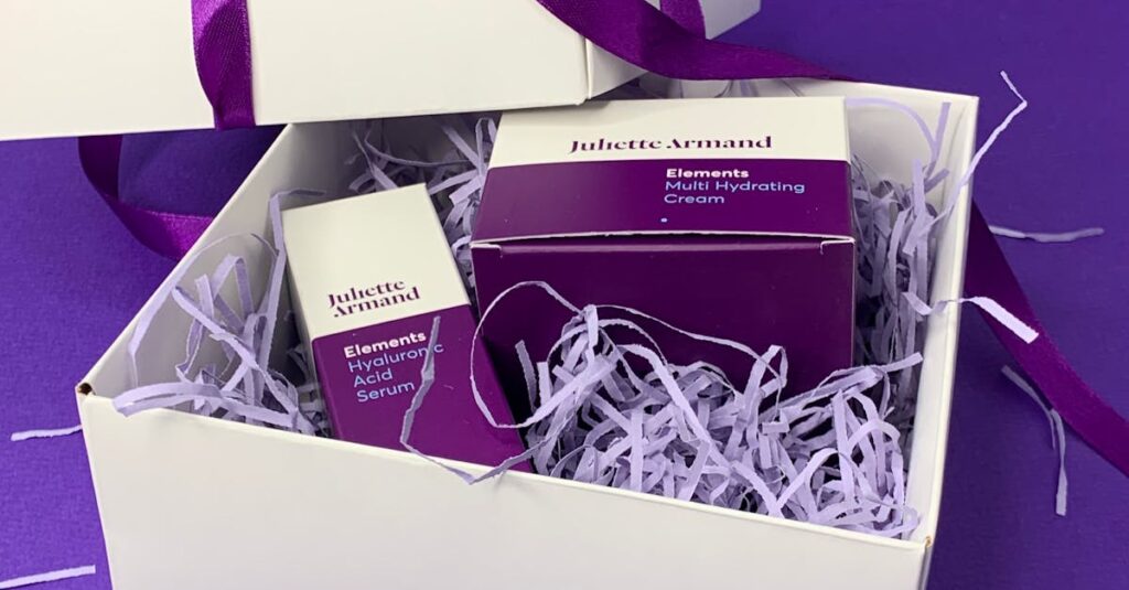 White gift box with skincare items, adorned with purple ribbon, perfect for any occasion.