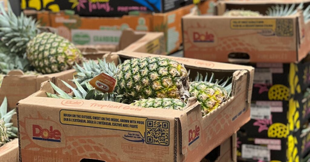 Boxes of fresh pineapples stacked in a supermarket aisle.