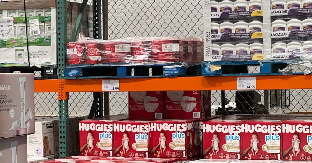 Stock photo of shelves filled with various baby diaper brands in a warehouse setting.