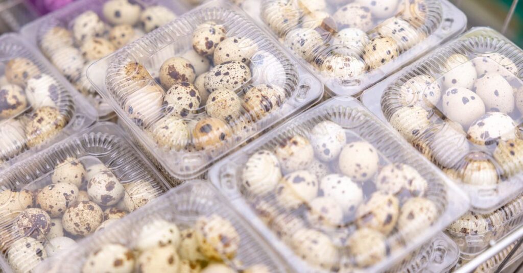 Quail eggs in transparent plastic packaging at a market. Ideal for culinary and food industry themes.