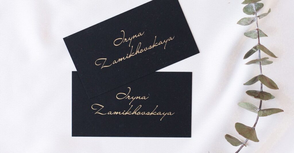 Minimalist black business cards placed on white fabric with eucalyptus twig for a modern look.