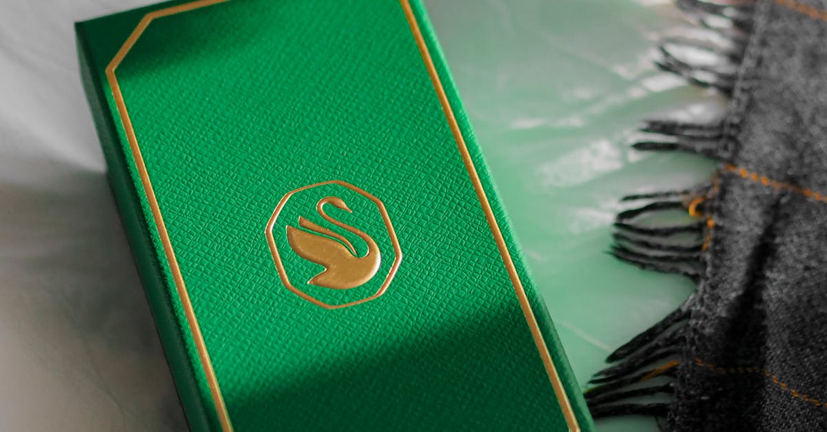 A luxurious green jewelry box with gold accents on a soft gray fabric background.