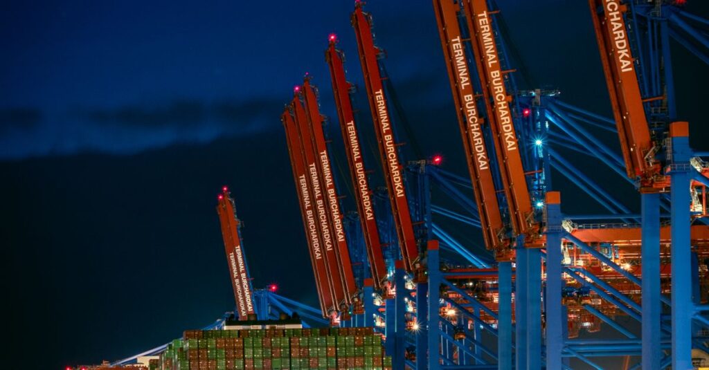 A large container ship docked at Hamburg's port, illuminated against the night sky.