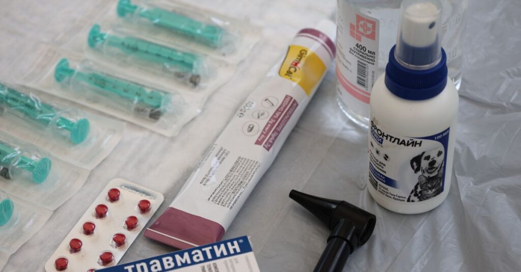Veterinary medical supplies including syringes, pills, and spray displayed on a table.