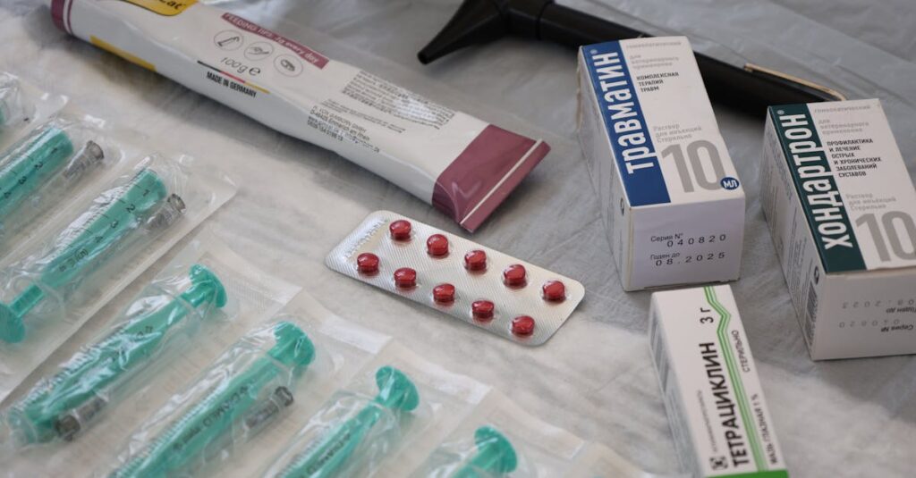 Flat lay of medical supplies including syringes, pharmaceuticals, and an otoscope on a table.