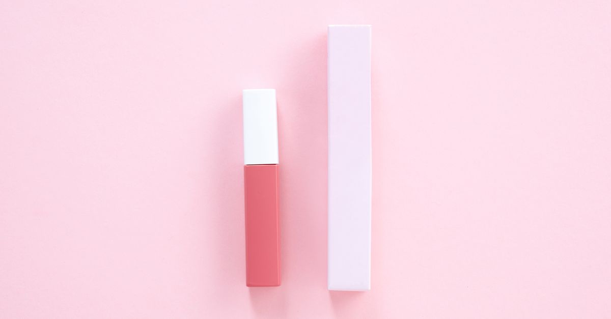 Elegant minimalist product shot of pink lip gloss with matching box on pastel background.