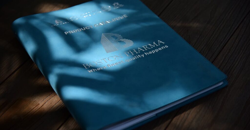 A blue folder with Boston Pharma branding in natural light on a wooden surface.