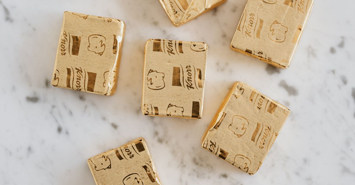 Overhead view of broth cubes in shiny golden package lying on white marble table
