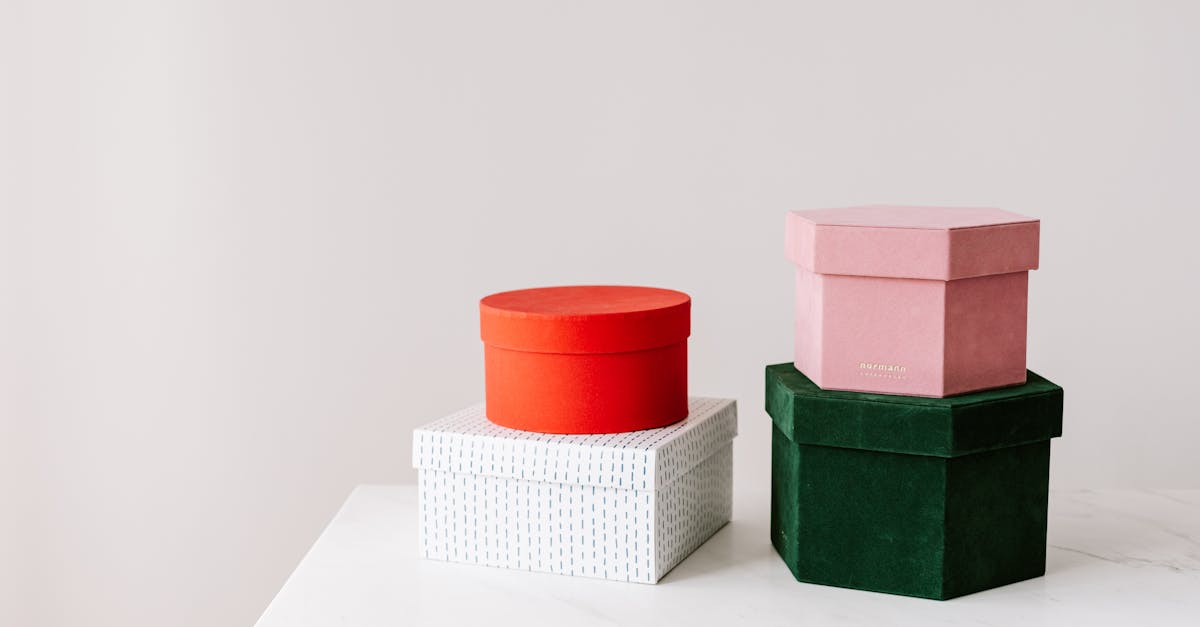 Gift boxes of different shapes and colors placed on each other served on white surface against gray background