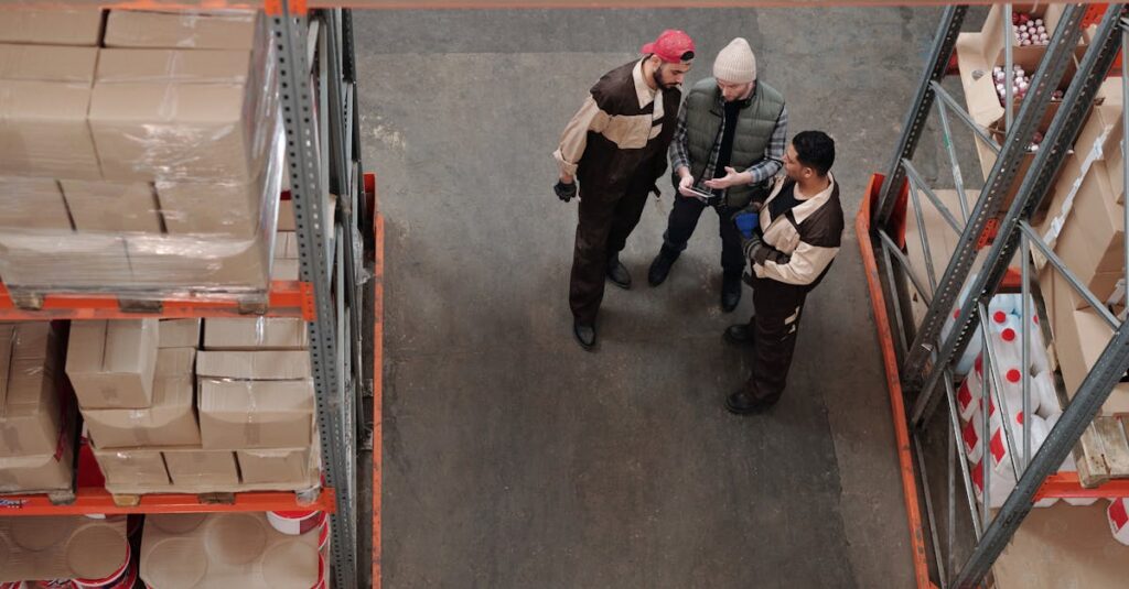 Three warehouse workers discussing logistics in an industrial storage area.