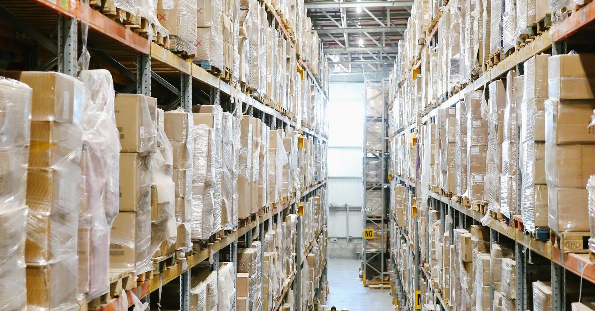 Spacious warehouse aisles lined with shelves stacked with boxes and packaging.