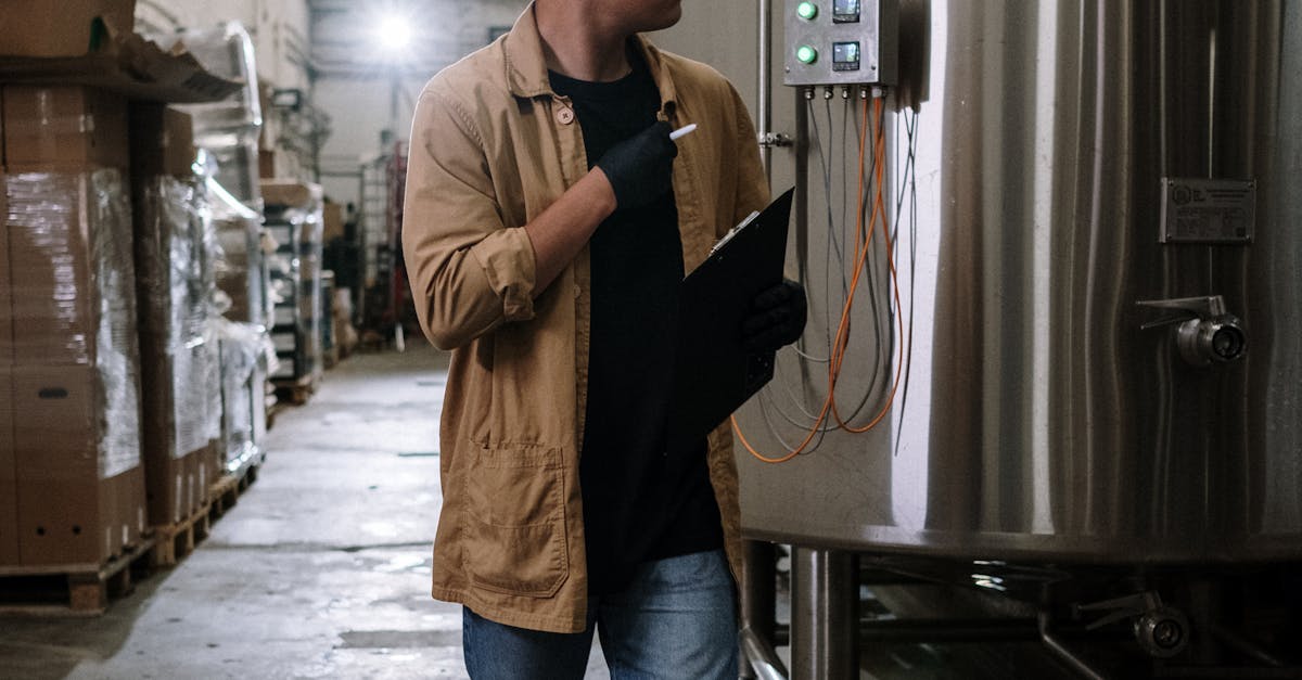 Man in brown jacket checking brewery tanks inside an industrial plant.
