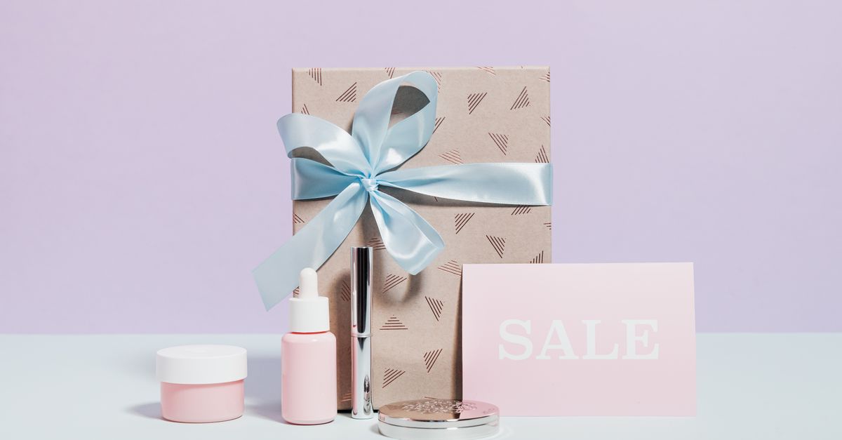 Stylish flat lay of beauty products and a gift with sale signage, perfect for promotions.