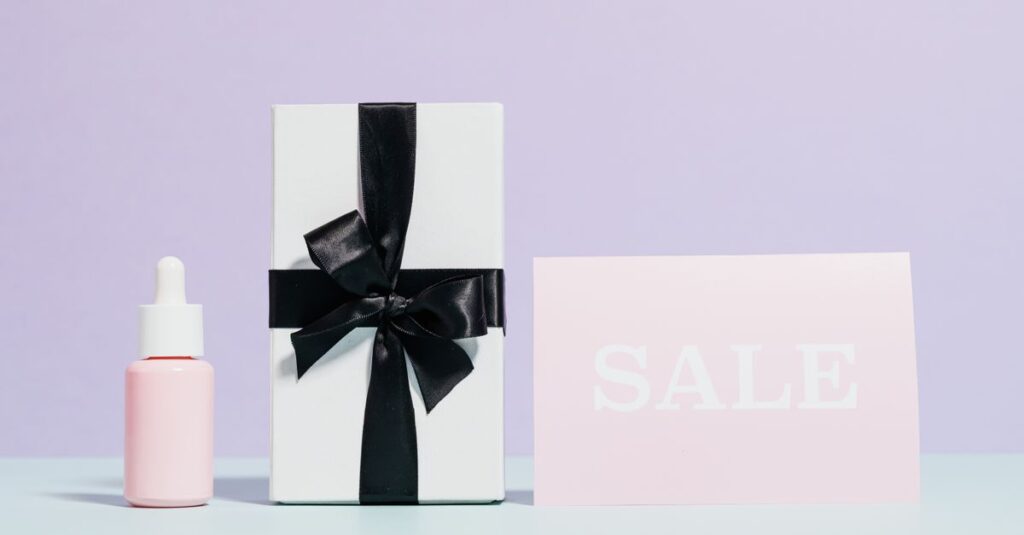 Elegant gift box with black ribbon beside a sale card, perfect for promotions.