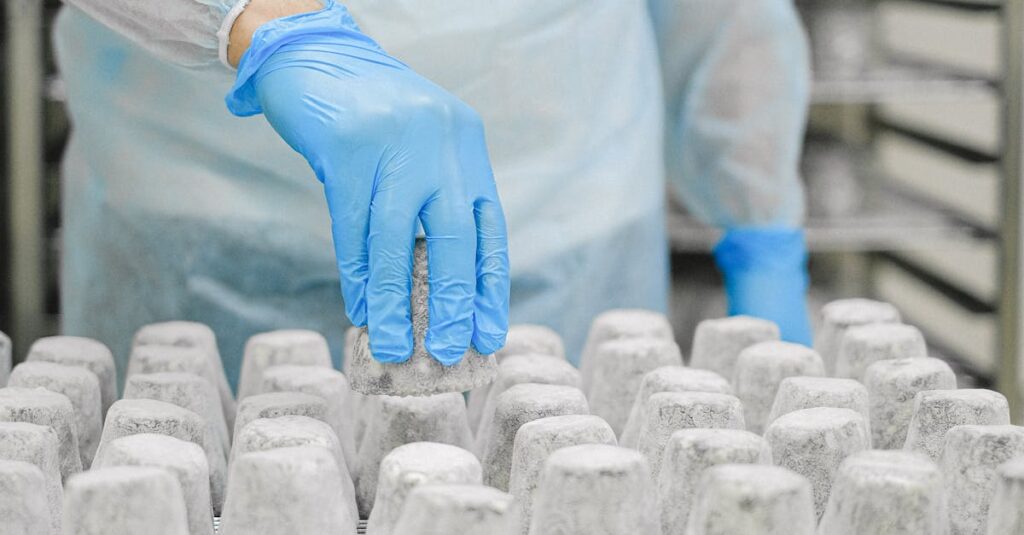 A worker in protective gear inspects matured cheese in an industrial setting, ensuring hygiene and safety standards.