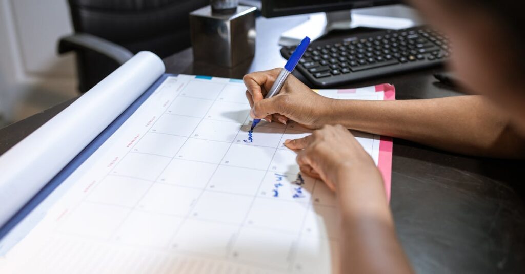 Close-up of a woman planning her schedule on a desk calendar in an office setting.