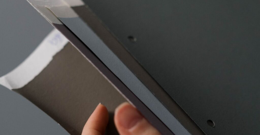 A close-up view of a hand holding paper samples, showcasing different textures and colors.
