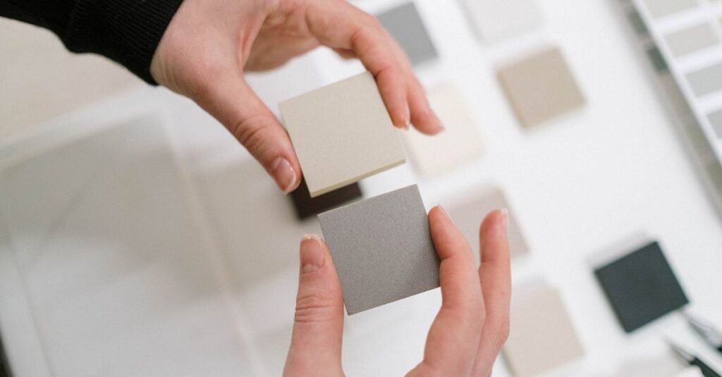 Hands holding neutral color swatches for interior design selection.