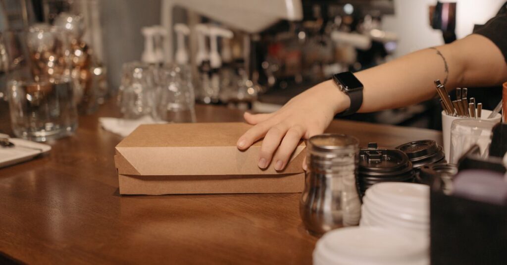 Barista handing over a takeout box at a café counter. Ideal for business and service imagery.
