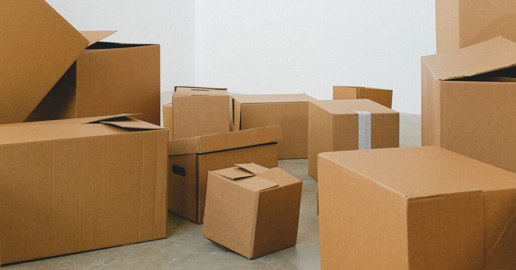 Heaps of different cardboard boxes on floor in rented house in daytime on white background