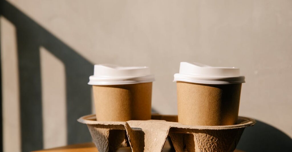 Cardboard cups with plastic lids on holder tray placed on wooden table casting a shadow