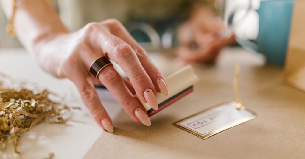 A close-up view of a manicured hand stamping a personalized tag, emphasizing creativity.