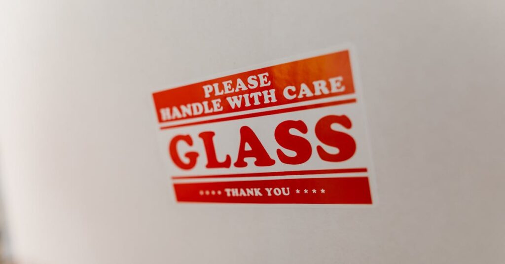 Close-up of a glass packaging label with 'Handle with Care' warning text on a white box.